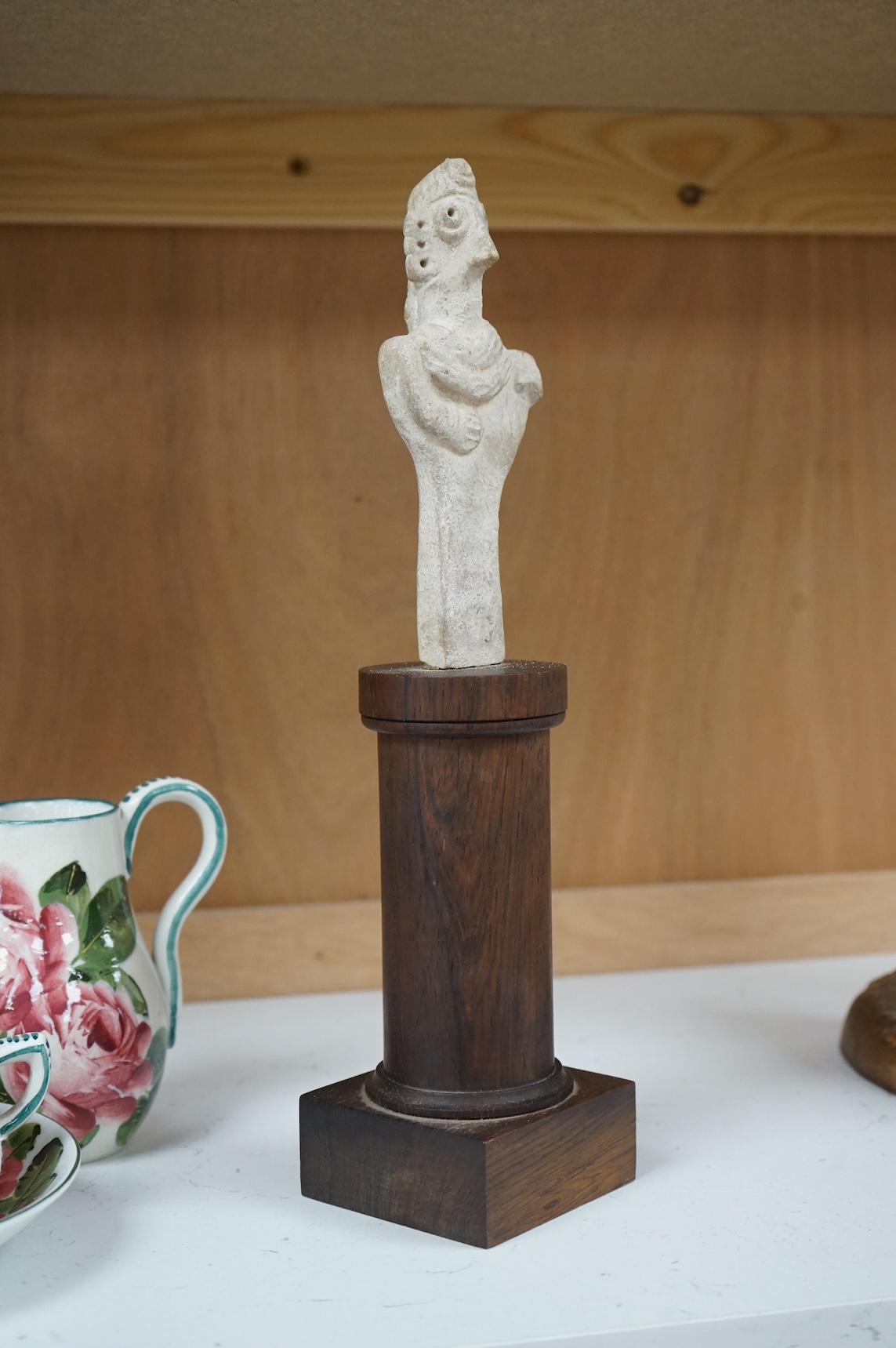 A Syro-Hittite pottery figure, on columnar rosewood stand, 29cm high